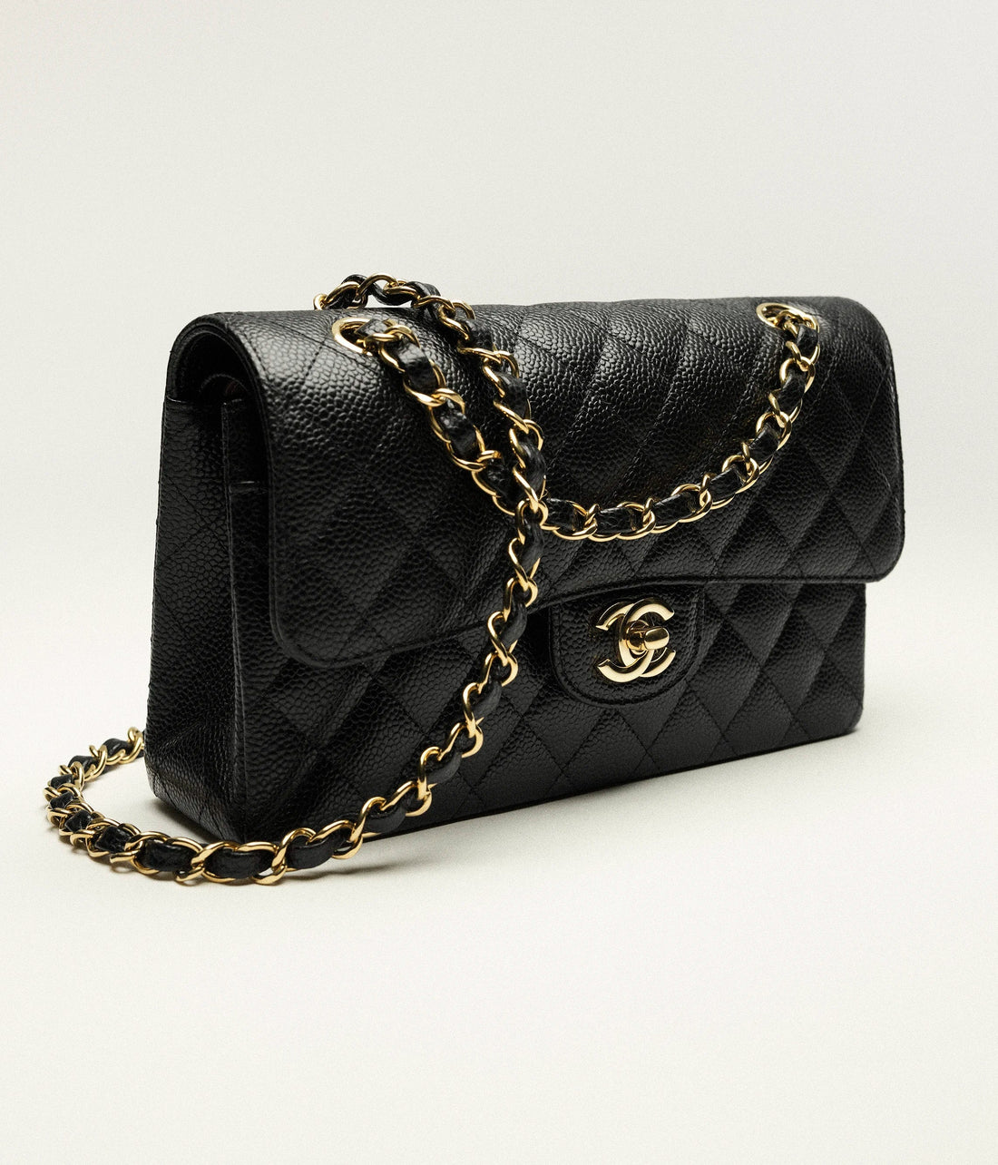 Product photo of the small Chanel Classic Flap bag in black with signature diamond quilting and gold hardware.