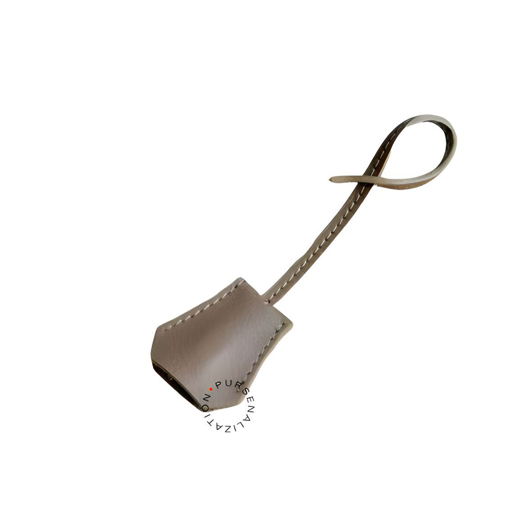 An image of a clochette leather charm for handbags accessories in the variety Foudre, a perfect blend of grey and brown.